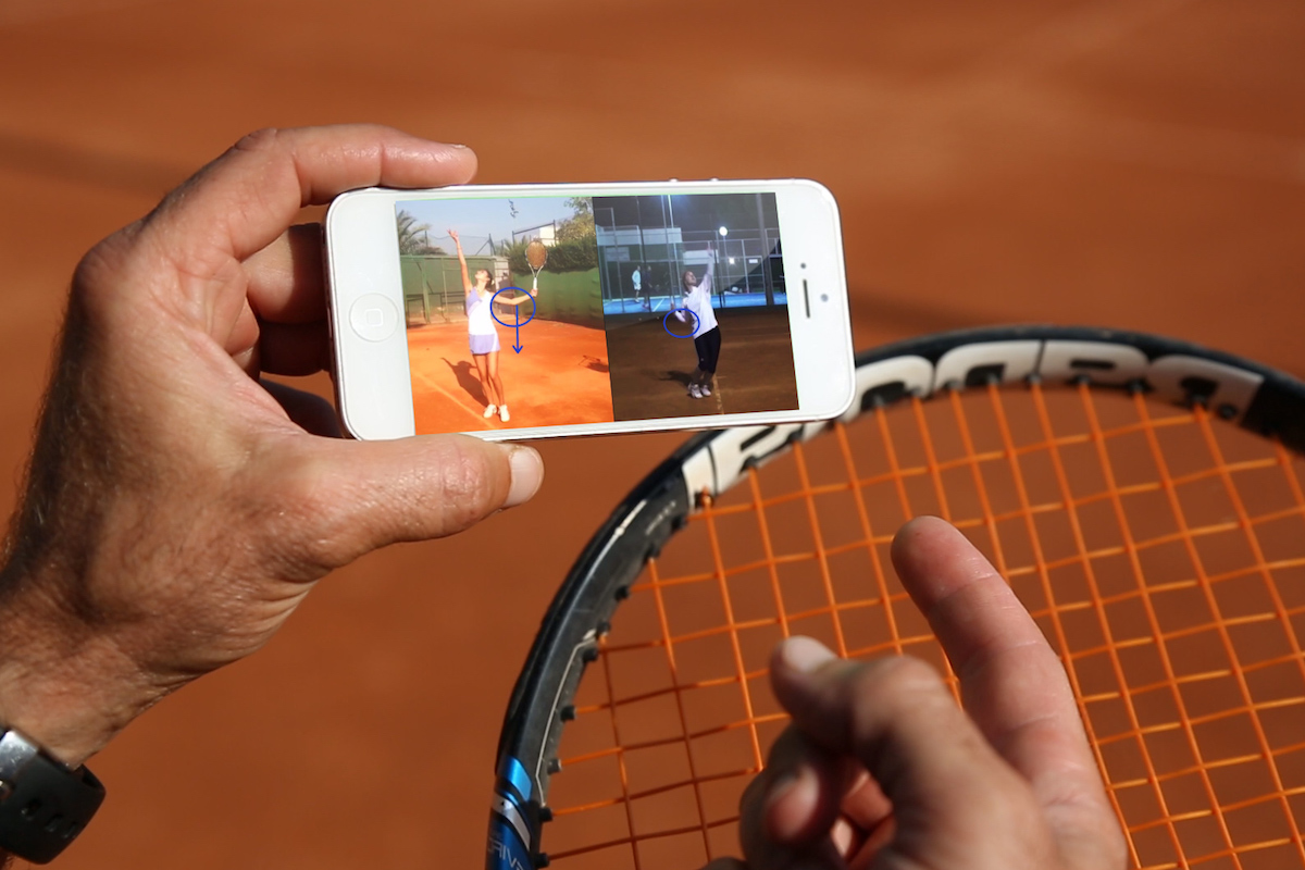Tennis coach and a female tennis player looking at the smartphone and analysing tennis serve on a clay tennis court in Barcelona